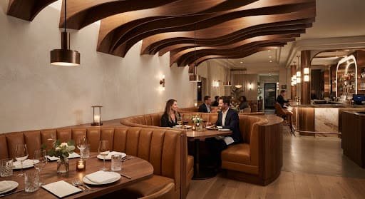 Fine dining restaurant with sculpted timber ceiling baffles and leather banquette booths